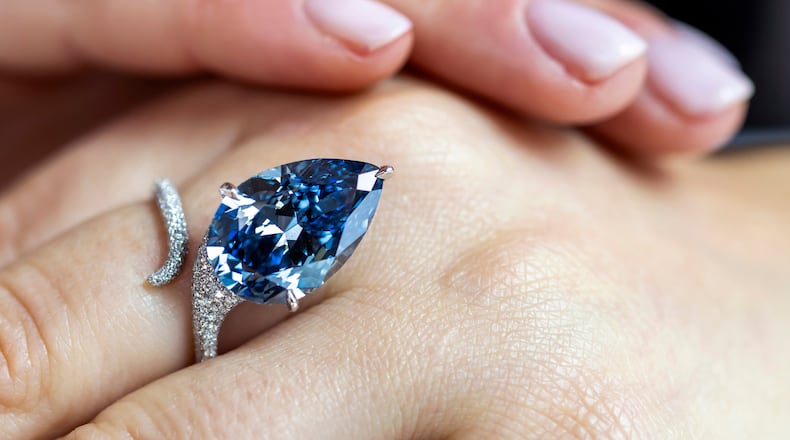 A Christie's employee displays the Mellon Blue, a fancy vivid blue pear-shaped diamond of 9.51 carats, during a preview at Christie's in Geneva, Switzerland, Friday, Nov. 7, 2025, ahead of an auction where it is estimated to sell for between 20 and 30 million US dollars. (Martial Trezzini/Keystone via AP)