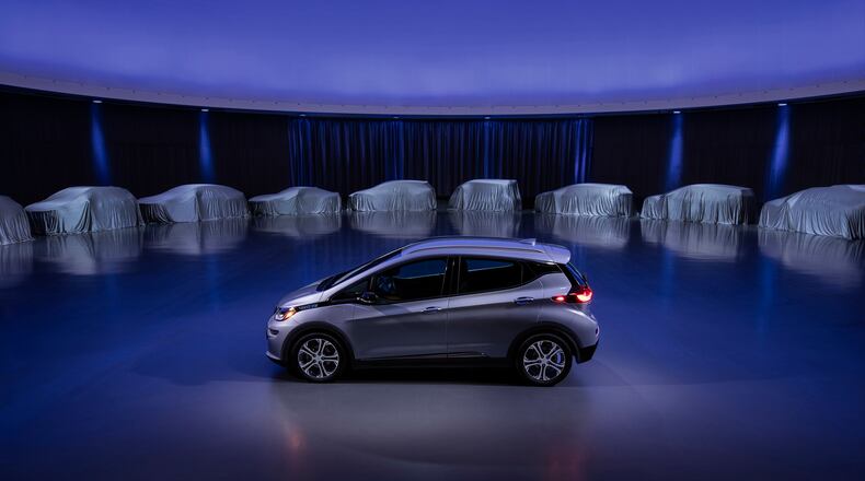 This photo provided by General Motors Co. shows a Chevrolet Bolt, surrounded by nine electric and fuel cell vehicles covered by tarps. Courtesy of GM via AP