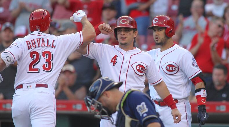 The Reds’ Adam Duvall, left, celebrates a home run with Scooter Gennett, center, and Eugenio Suarez in teh first inning against the Brewers on Tuesday, June 27, 2017, at Great American Ball Park in Cincinnati. David Jablonski/Staff