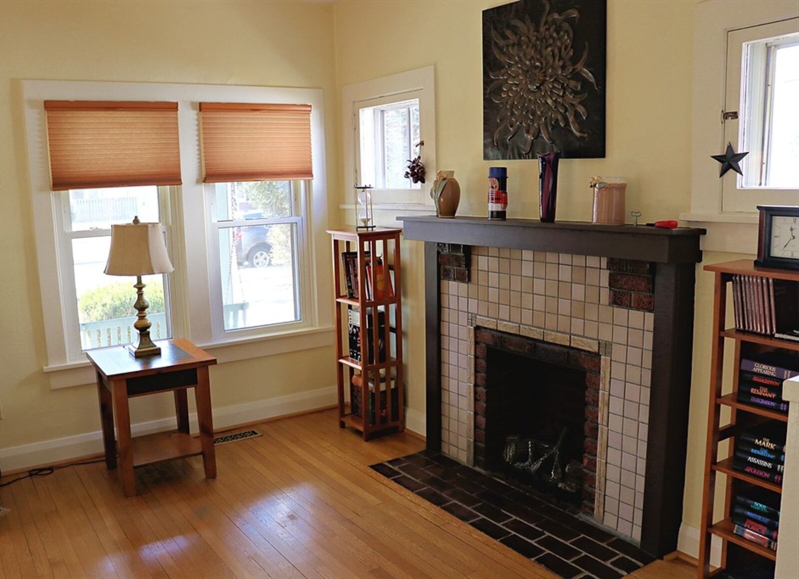 The formal entry opens from the covered front porch into the living room, which has a decorative fireplace with a ceramic-tile surround and wood-beam mantel. 
