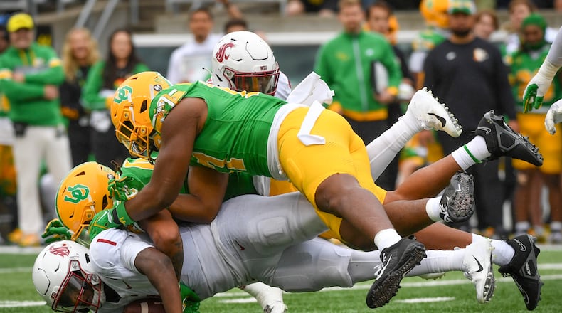 Washington State quarterback Cameron Ward (1) is sacked by Oregon linebackers Jestin Jacobs, center, and Blake Purchase, top, during the second half of an NCAA college football game Saturday, Oct. 21, 2023, in Eugene, Ore. (AP Photo/Andy Nelson)