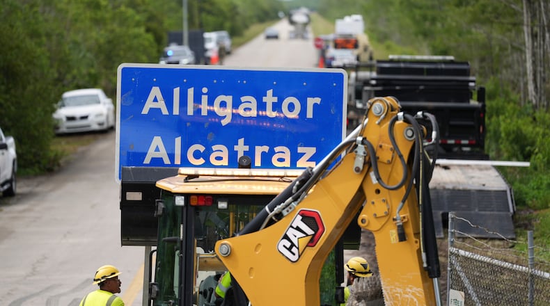 FILE - A loader holds a sign reading "Alligator Alcatraz" in its bucket as workers install it at the entrance to a new migrant detention facility at Dade-Collier Training and Transition facility, July 3, 2025, in Ochopee, Fla. (AP Photo/Rebecca Blackwell)