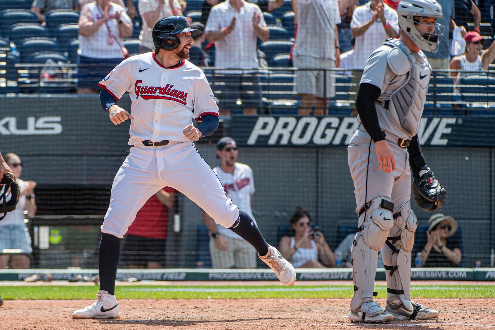 Cleveland Guardians' Daniel Schneemann, left, scores on an RBI single by Steven Kwan as Detroit Tigers' Dillon Dingler, right, looks for a throw during the inning of a baseball game, Sunday, July 6, 2025, in Cleveland. (AP Photo/Phil Long)