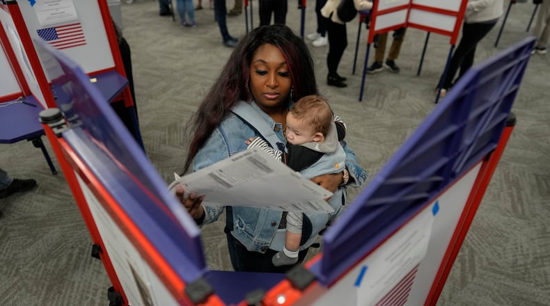 First-time voter Kayria Hildebran holds baby Kayden Hildebran as she fills out her ballot during in-person early voting at Hamilton County Board of Elections, Thursday, Oct. 31, 2024, in Cincinnati. (AP Photo/Gail Burton)