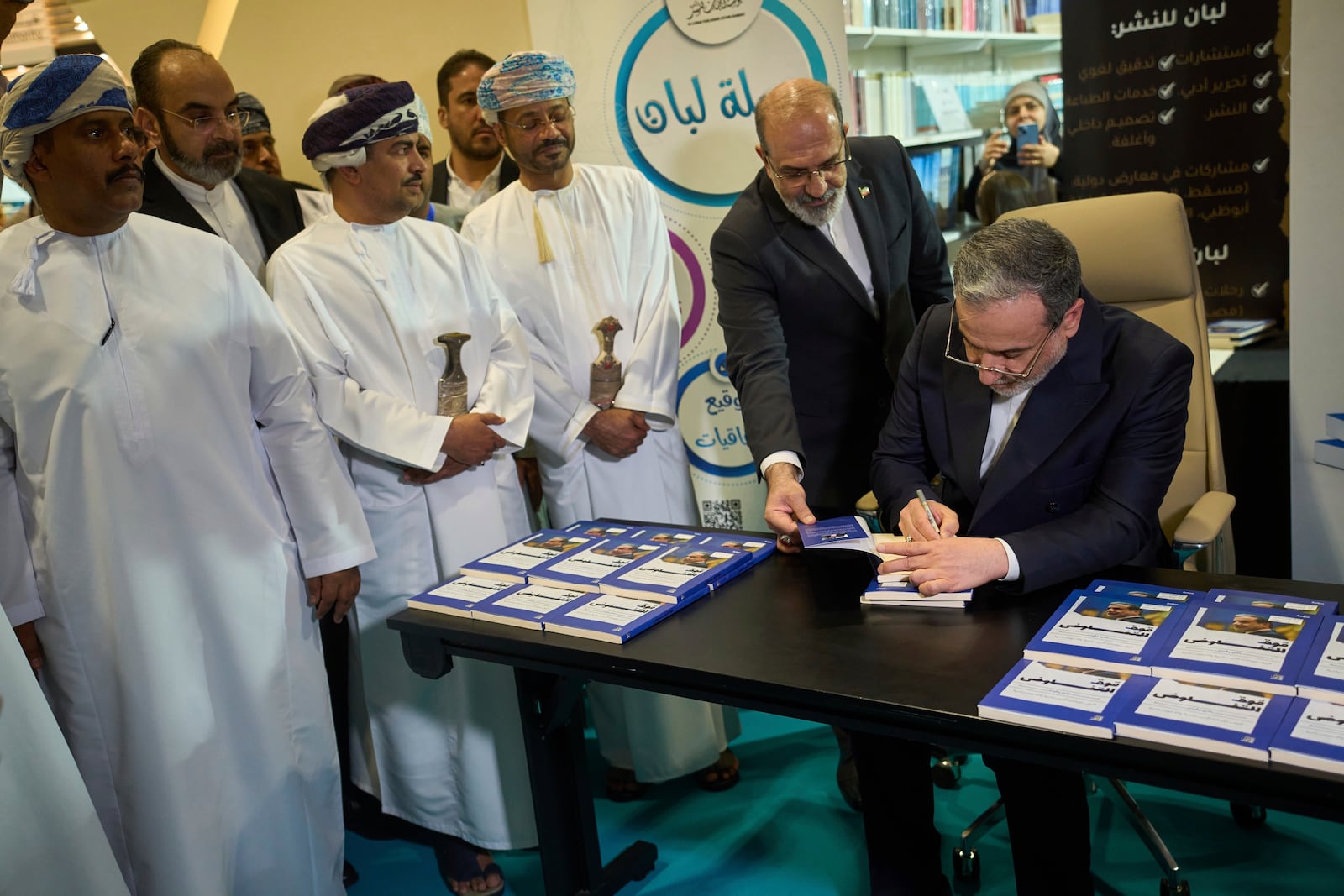 Iranian Foreign Minister Abbas Araghchi, signs a copy of his book "The Power of Negotiation" at the Muscat International Book Fair in Oman, Friday, April 25, 2025. (AP Photo/ Fatima Shbair)