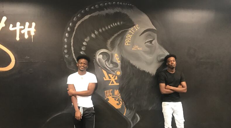 Nipsey Hussle, the late Grammy-winning rapper, social activist and entrepreneur has been a big inspiration for Mustafa Ibrahim (right) and Herbert Chongwain (left) when they opened their store 48th Clothing at the Northwest Plaza. Behind them in their store is the large mural of Hussle done by Lycia Cromer, who graduated from the Miami Valley School and is a student at the Art Academy of Cincinnati. Tom Archdeacon/STAFF