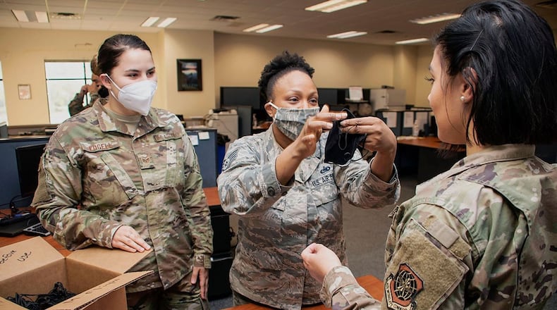 Staff Sgt. Kleo Edgell (left), 60th Logistics Readiness Squadron aircraft parts store supervisor, and Tech. Sgt. Erica Dixon (center), 60th LRS NCO in charge of the aircraft parts store, issue a cloth face cover to Senior Airman Megan Perez and explains how to wear it, at Travis Air Force Base, Calif., April 14. Travis AFB officials purchased the masks using an expedited Air Force Installation Contracting Center blanket purchase agreement. (U.S. Air Force photo/Senior Airman Christian Conrad)