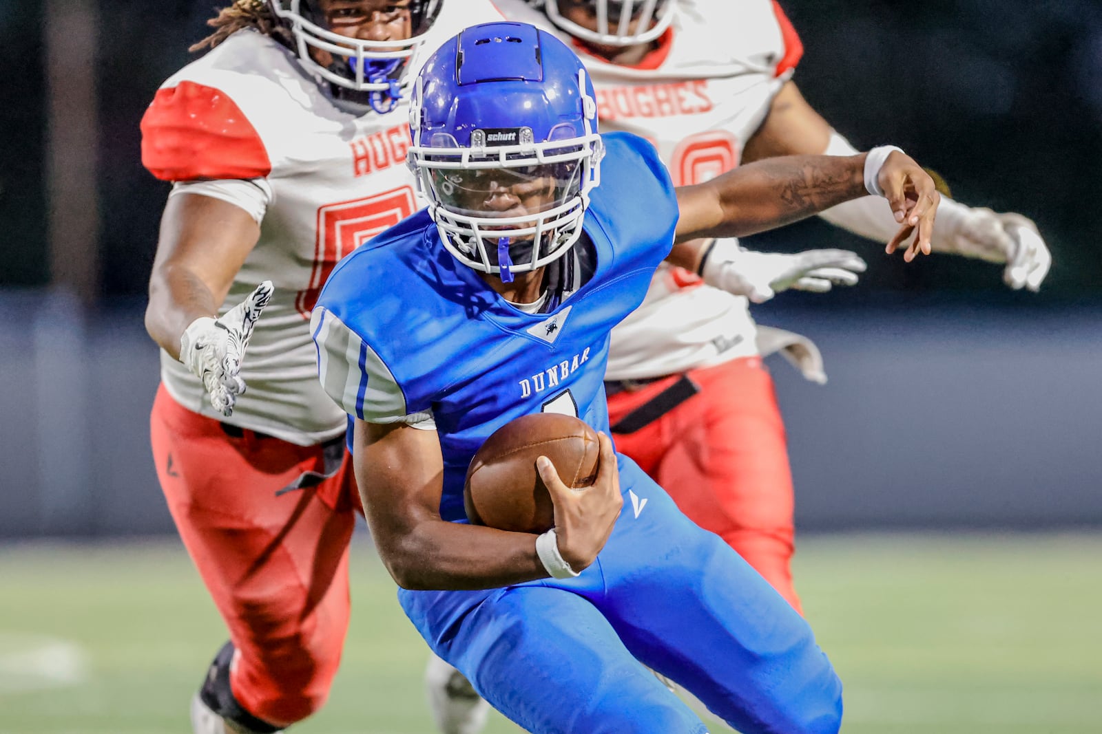 Dunbar High School junior Tray'Von Carr runs past a pair of Cincinnati Hughes defensive players during their game on Thursday, Aug. 21 at Welcome Stadium. The Big Red won 20-0. MICHAEL COOPER / STAFF