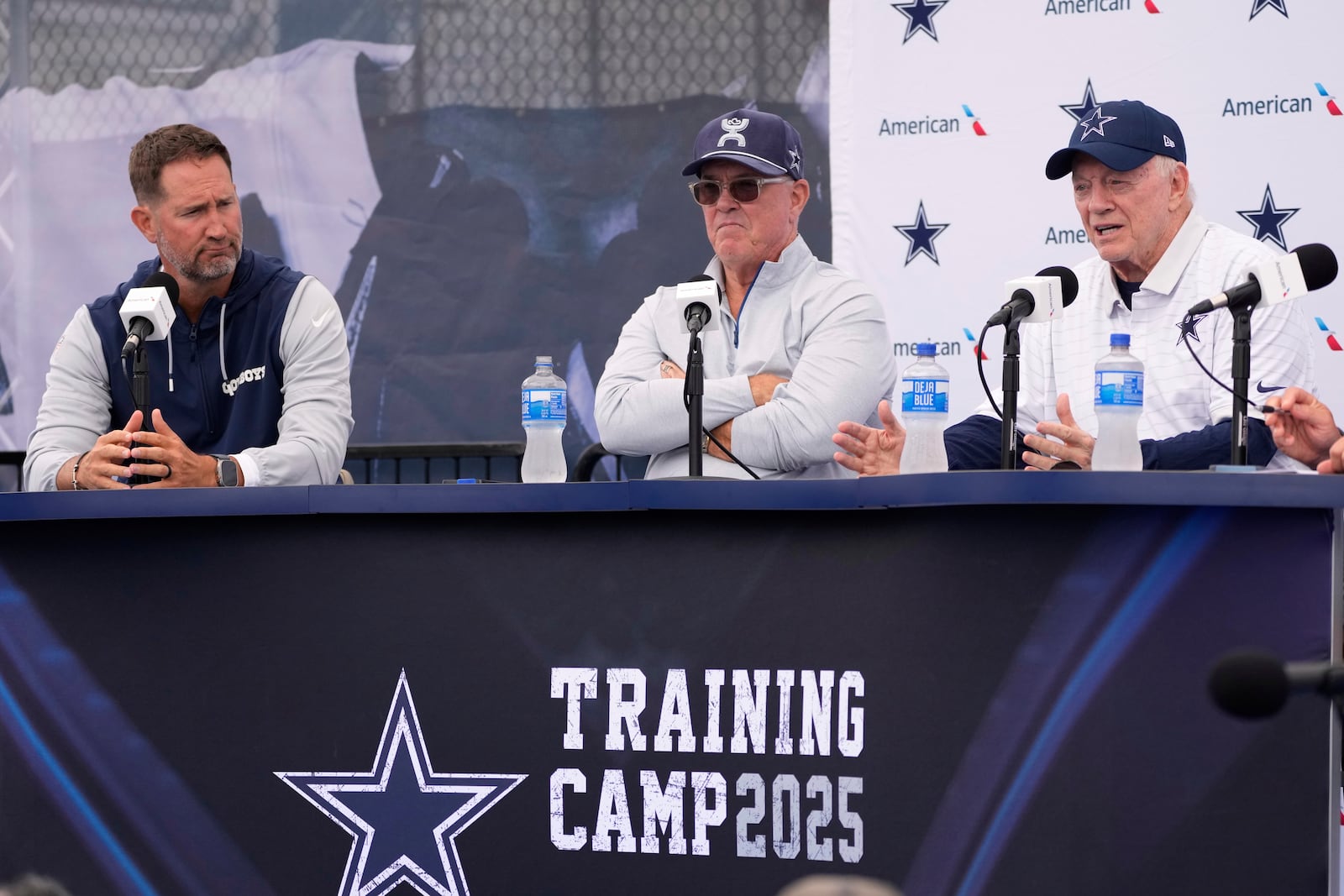 Jerry Jones, right, Dallas Cowboys owner, president, and general manager speaks to reporters as Cowboys head coach Brian Schottenheimer, left, and Stephen Jones, Dallas Cowboys co-owner, executive vice president, CEO, and director of player personnel listen during a news conference to open training camp Monday, July 21, 2025, in Oxnard, Calif. (AP Photo/Mark J. Terrill)