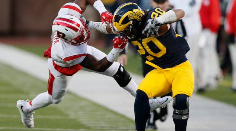 Michigan's Drake Johnson is dragged down with a face mask penalty on Rutgers' Kiy Hester, setting up a Michigan touchdown late in the second quarter on Saturday, Nov 7, 2015 in Ann Arbor, Mich. (Julian H. Gonzalez/Detroit Free Press/TNS)