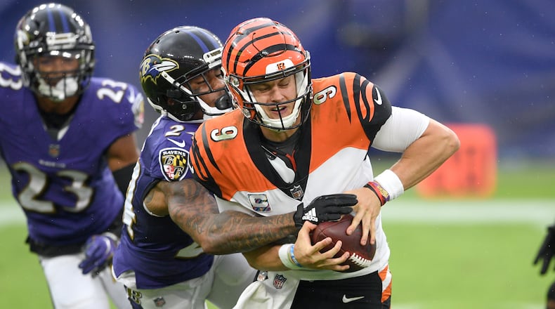 Baltimore Ravens cornerback Marcus Peters, left, forces a fumble on Cincinnati Bengals quarterback Joe Burrow during the second half of an NFL football game, Sunday, Oct. 11, 2020, in Baltimore. The ball bounced out of bounds and the Bengals retained possession. (AP Photo/Nick Wass)