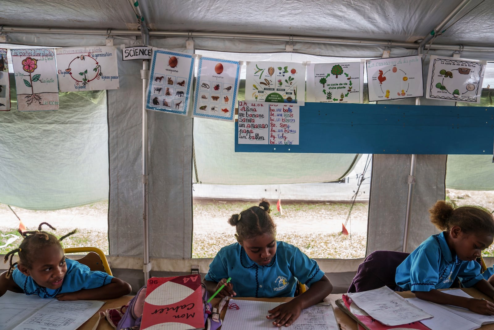 Students work in a tented classroom at Sainte Jeanne D'Arc school in Port Vila, Vanuatu, Thursday, July 17, 2025. (AP Photo/Annika Hammerschlag)