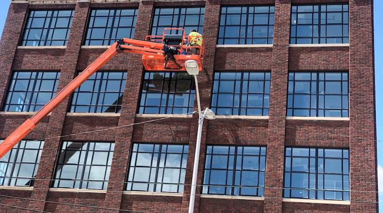 Crews work on the exterior of the Graphic Arts Lofts building in downtown Dayton on Monday. CORNELIUS FROLIK / STAFF