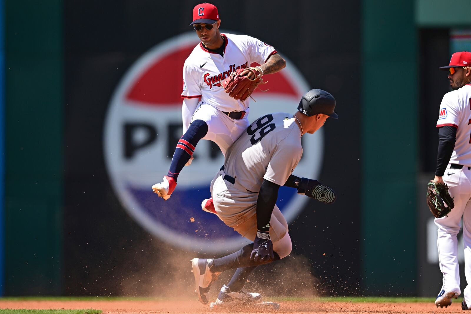 Cleveland Guardians shortstop Brayan Rocchio attempts to avoid New York Yankees' Aaron Judge after a slide at second base during the fourth inning of a baseball game Wednesday, April 23, 2025, in Cleveland. Judge was safe at second on a fielder's choice hit by Cody Bellinger. (AP Photo/David Dermer)