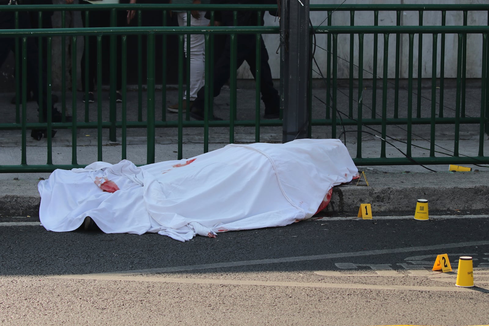 A body lies covered at the site where the personal secretary and an advisor to Mexico City's mayor were killed by gunmen on a motorcycle, in Mexico City, Tuesday, May 20, 2025. (AP Photo/Tristan Velazquez)
