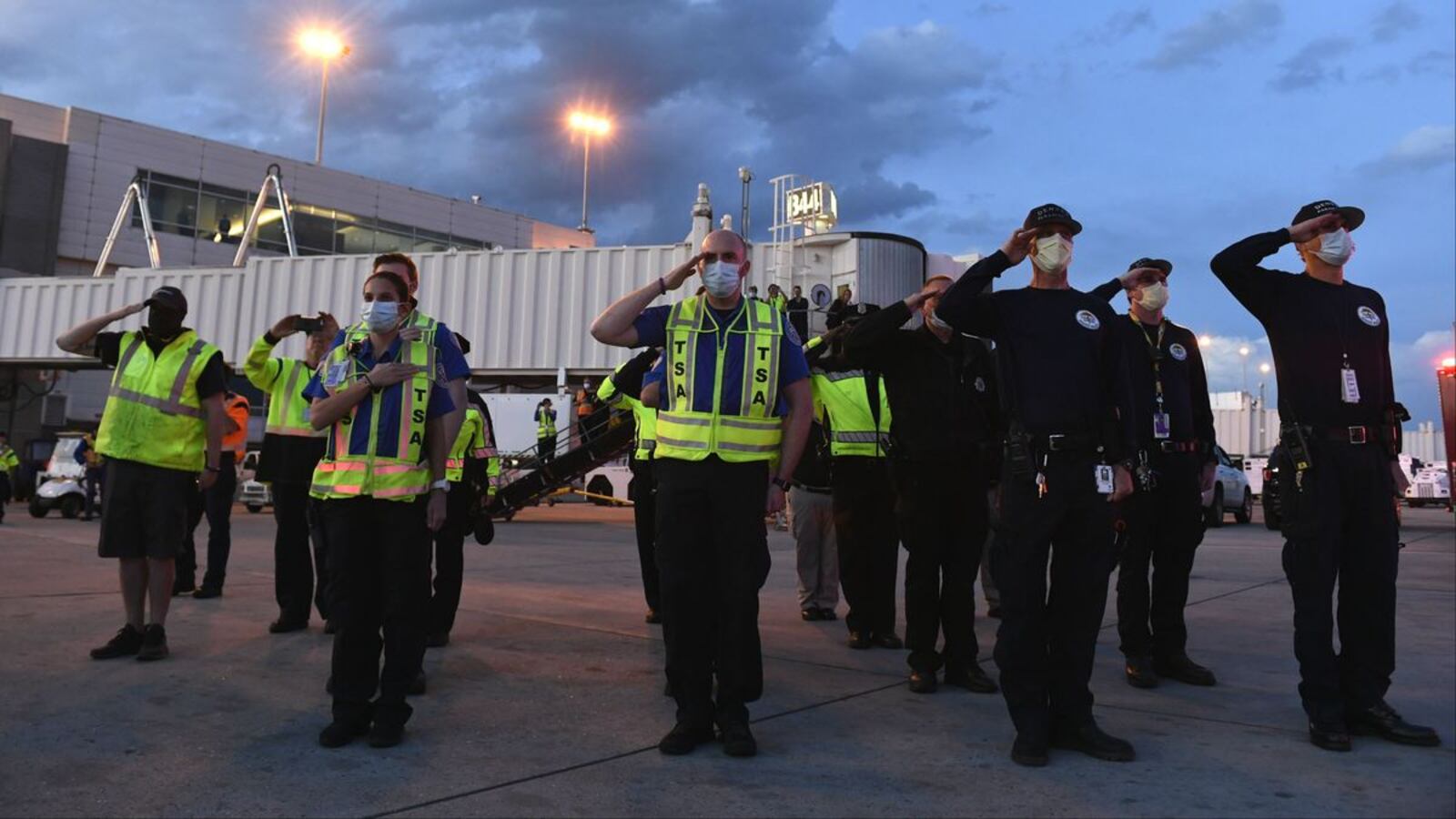 Transportation Security Administration agents and Denver paramedics salute the casket carrying the body of paramedic Paul Cary at Denver International Airport on Sunday, May 3, 2020, in Denver, Colo. Cary, 66, died Thursday, April 30, of coronavirus complications after volunteering to help combat the pandemic in New York City. (Helen H. Richardson/The Denver Post via AP)