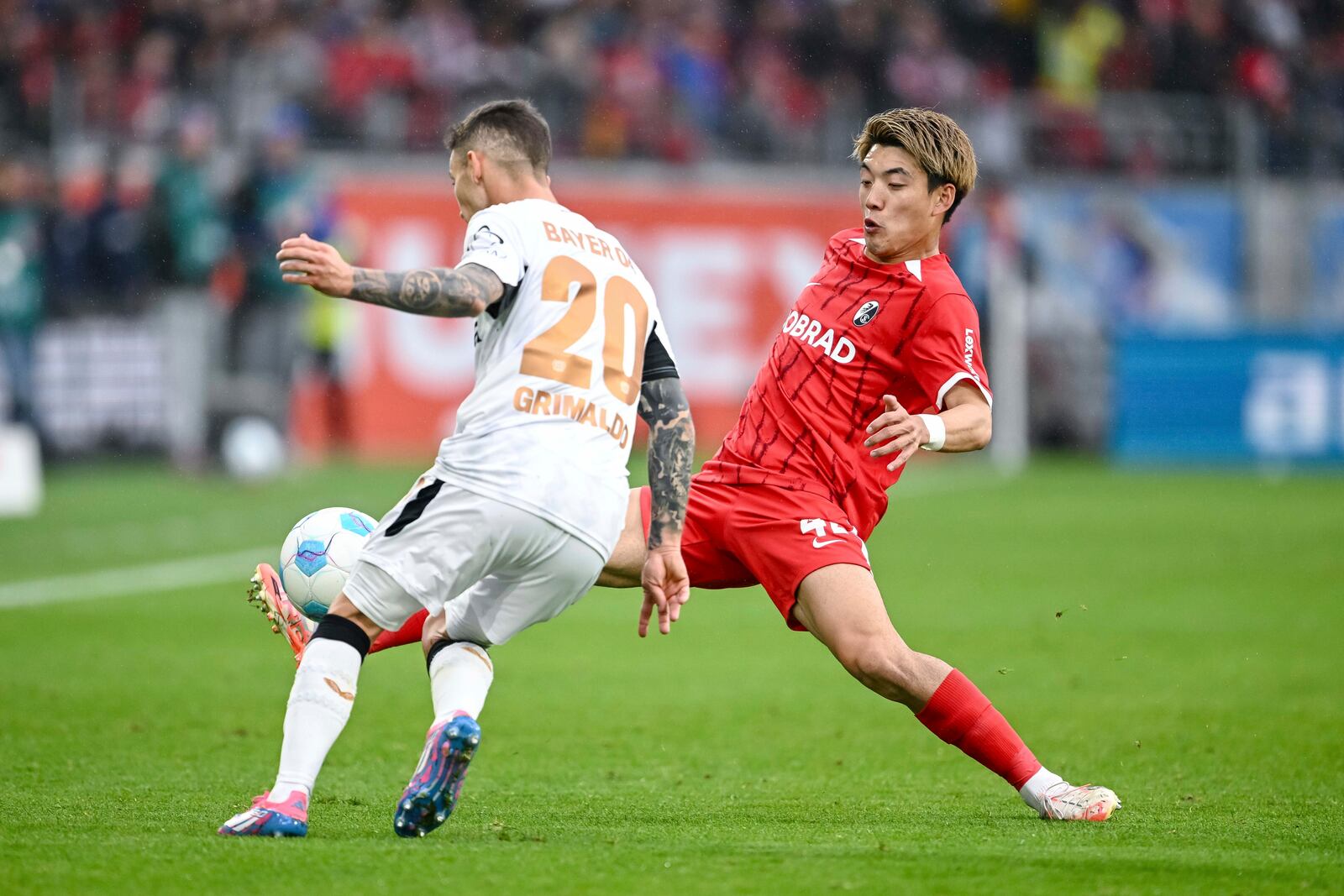 Leverkusen's Alejandro Grimaldo, left, vies for the ball with Freiburg's Ritsu Doan, during the German Bundesliga soccer match between, SC Freiburg and Bayer Leverkusen, at Europa-Park Stadium, in Freiburg im Breisgau, Germany, Sunday, May 4, 2025. (Harry Langer/dpa via AP)