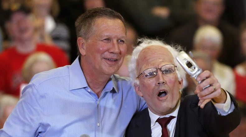 Republican presidential candidate, Ohio Gov. John Kasich poses for a selfie with a Bernie Sanders impersonator at the end of a town hall meeting, Wednesday, March 9, 2016, in Palatine, Ill. (AP Photo/Charles Rex Arbogast)