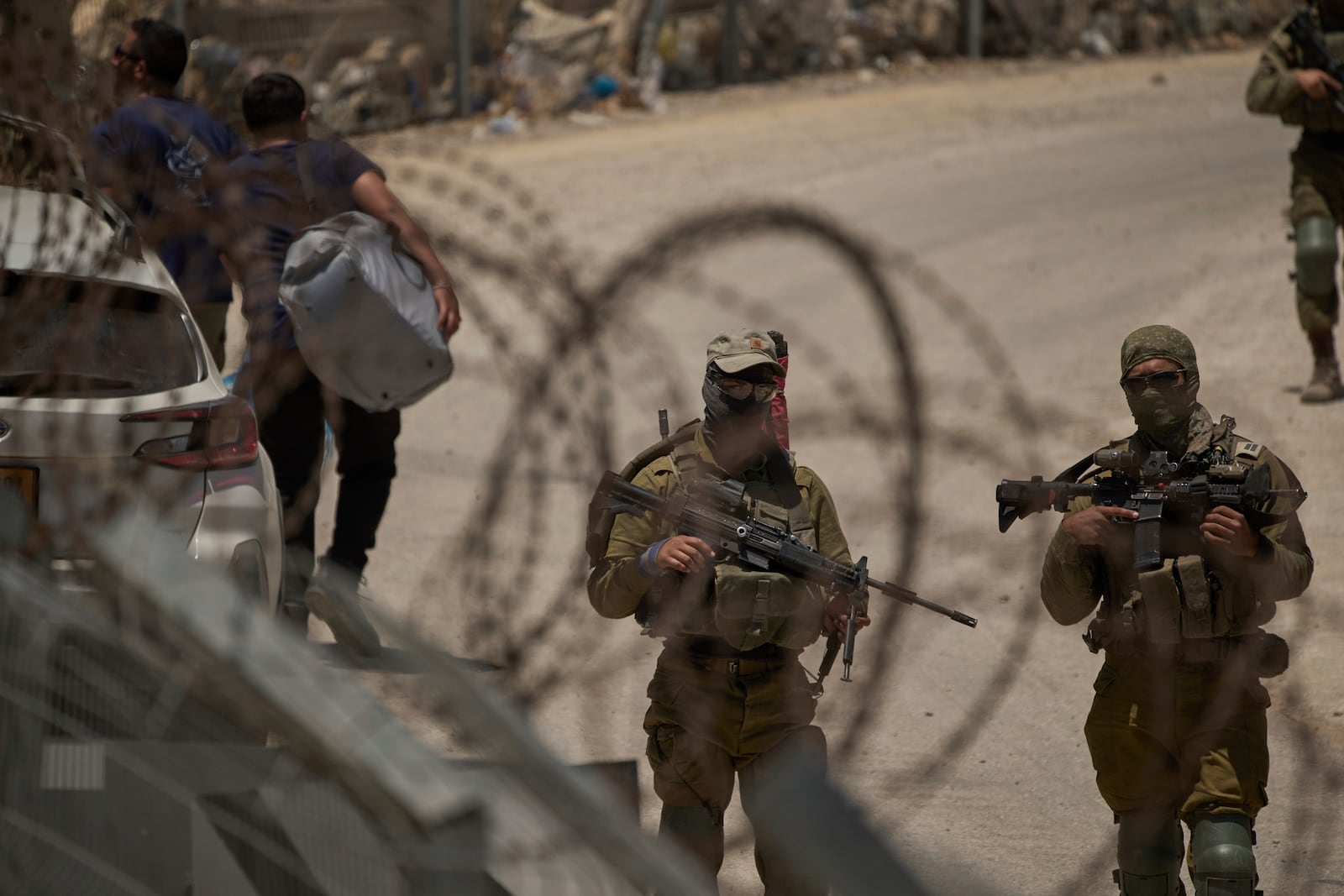 Israeli soldiers stand guard as Syrian Druze people cross back into Syria at the Israeli-Syrian border, in the Israeli-controlled Golan Heights town of Majdal Shams, Thursday, July 17, 2025. (AP Photo/Leo Correa)