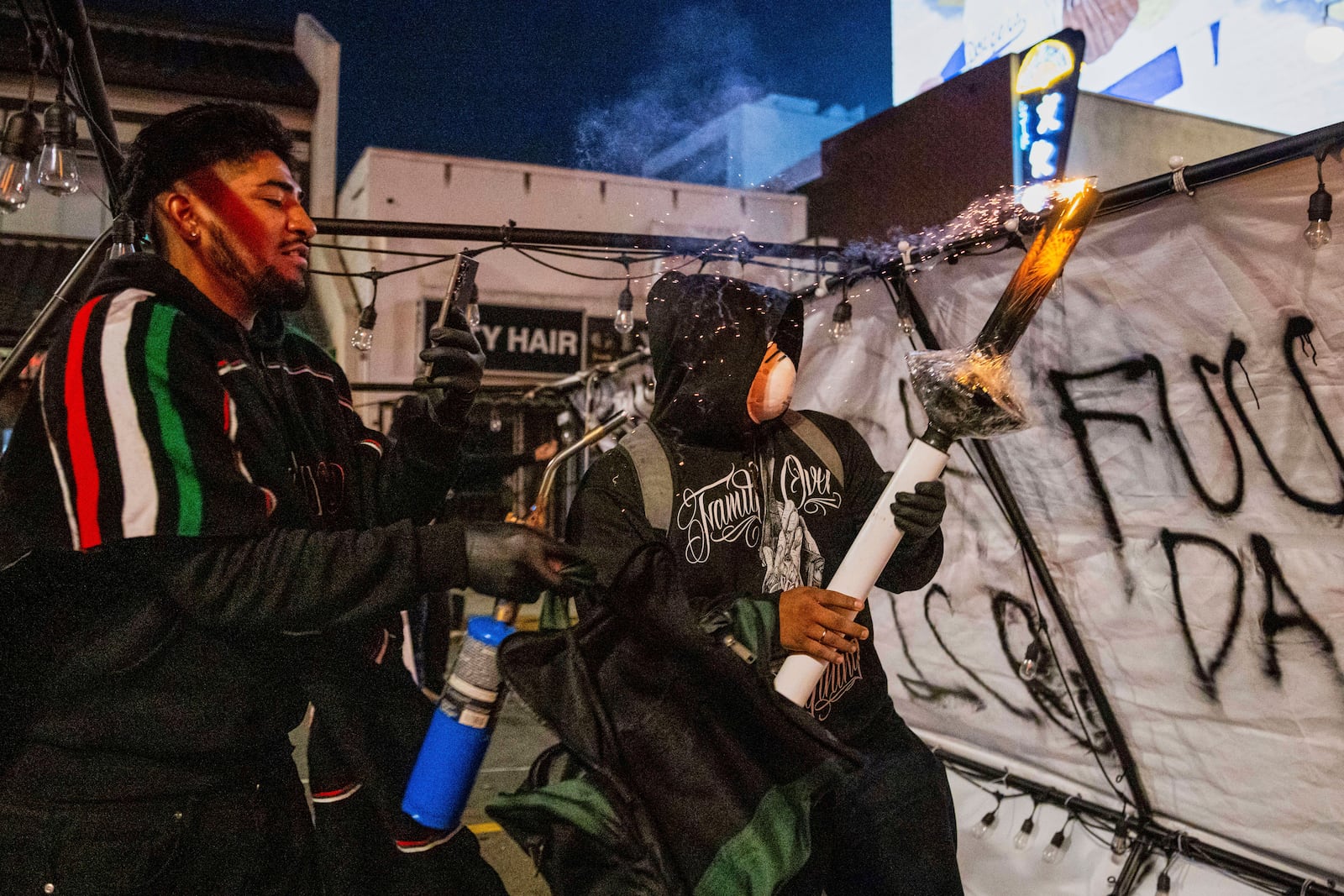 Protestors prepare to launch projectiles during protests over the Trump administration's immigration raids in Los Angeles, Monday, June 9, 2025. (AP Photo/Ethan Swope)