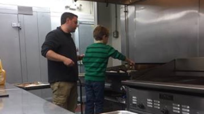 Adam Baumgarten of Bernstein's Fine Catering makes cooking latkes a family affair with the help of his son. (CONTRIBUTED)
