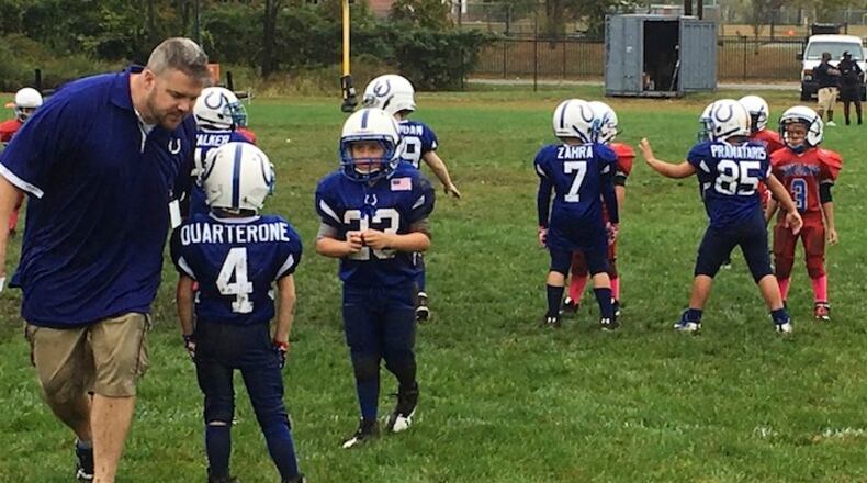 In this Sunday, Oct. 8, 2017 photo, coach John Galligan, left, directs players during a Rookie Tackle youth football game in Islip, N.Y. USA Football has introduced the pilot program called Rookie Tackle, a scaled down version of football for young players. (AP Photo/Ralph Russo)