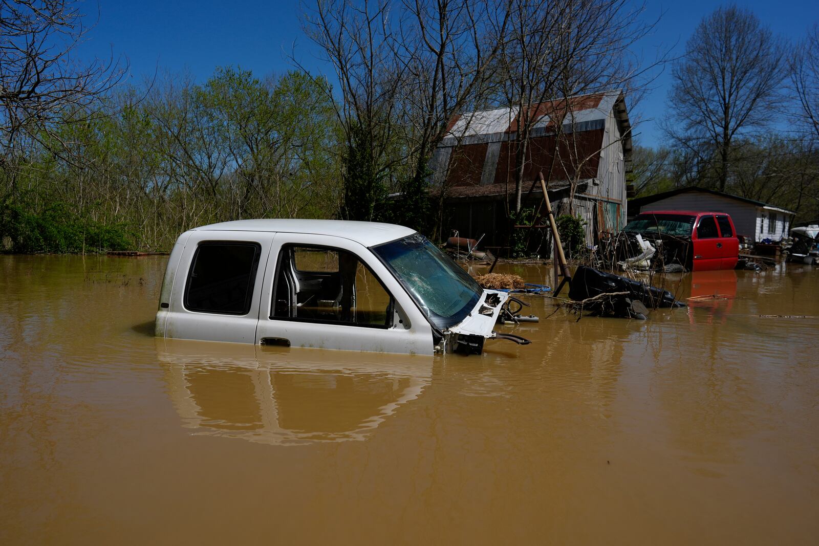 Vehicles sit partially submerged by Kentucky River floodwaters at a barnyard in Lockport, Ky., Tuesday, April 8, 2025. (AP Photo/Carolyn Kaster)