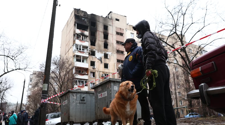 Local residents walk a dog near a damaged apartment building hit by Russian drone in Zaporizhzhia, Ukraine, Thursday, Feb. 26, 2026. (AP Photo/Kateryna Klochko)