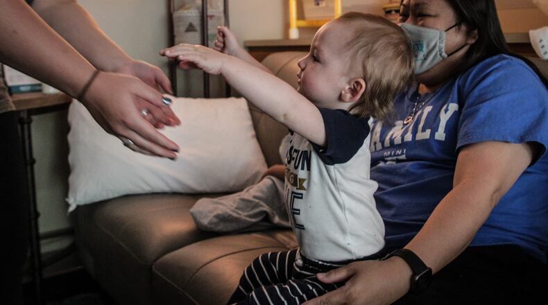 One year old Calvin Gray is handed off by lead Early Childhood Education Center teacher, Jennie Camp to his mom, Madison Gray Friday afternoon May 14, 2021. The day care has helped Gray stay in school and graduate at a faster pace. JIM NOELKER/STAFF