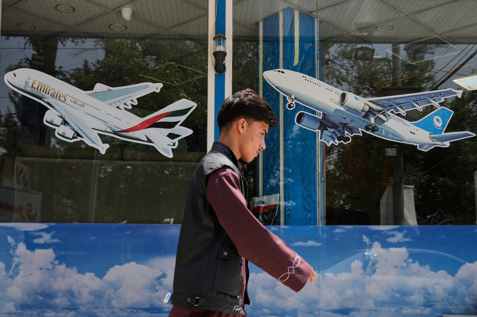 An Afghan man passes in front of an air travel agency in Kabul, Afghanistan, Thursday, June 5, 2025. (AP Photo/Ebrahim Noroozi)