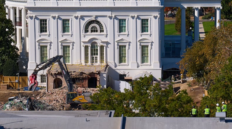 Construction workers, bottom right, atop the U.S. Treasury, watch as work continues on a largely demolished part of the East Wing of the White House, Thursday, Oct. 23, 2025, in Washington, before construction of a new ballroom. (AP Photo/Jacquelyn Martin)
