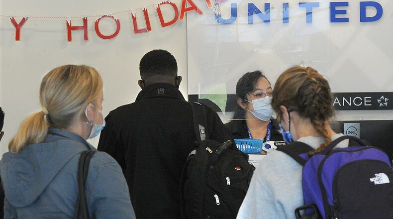 Holiday travelers line up at the United Airlines ticket desk at the Dayton International Airport on Monday, Dec. 20, 2021. MARSHALL GORBY\STAFF