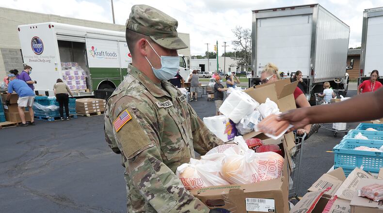 Members of the National Guard help carry a person's food to their car at the Second Harvest Food Bank Friday. BILL LACKEY/STAFF
