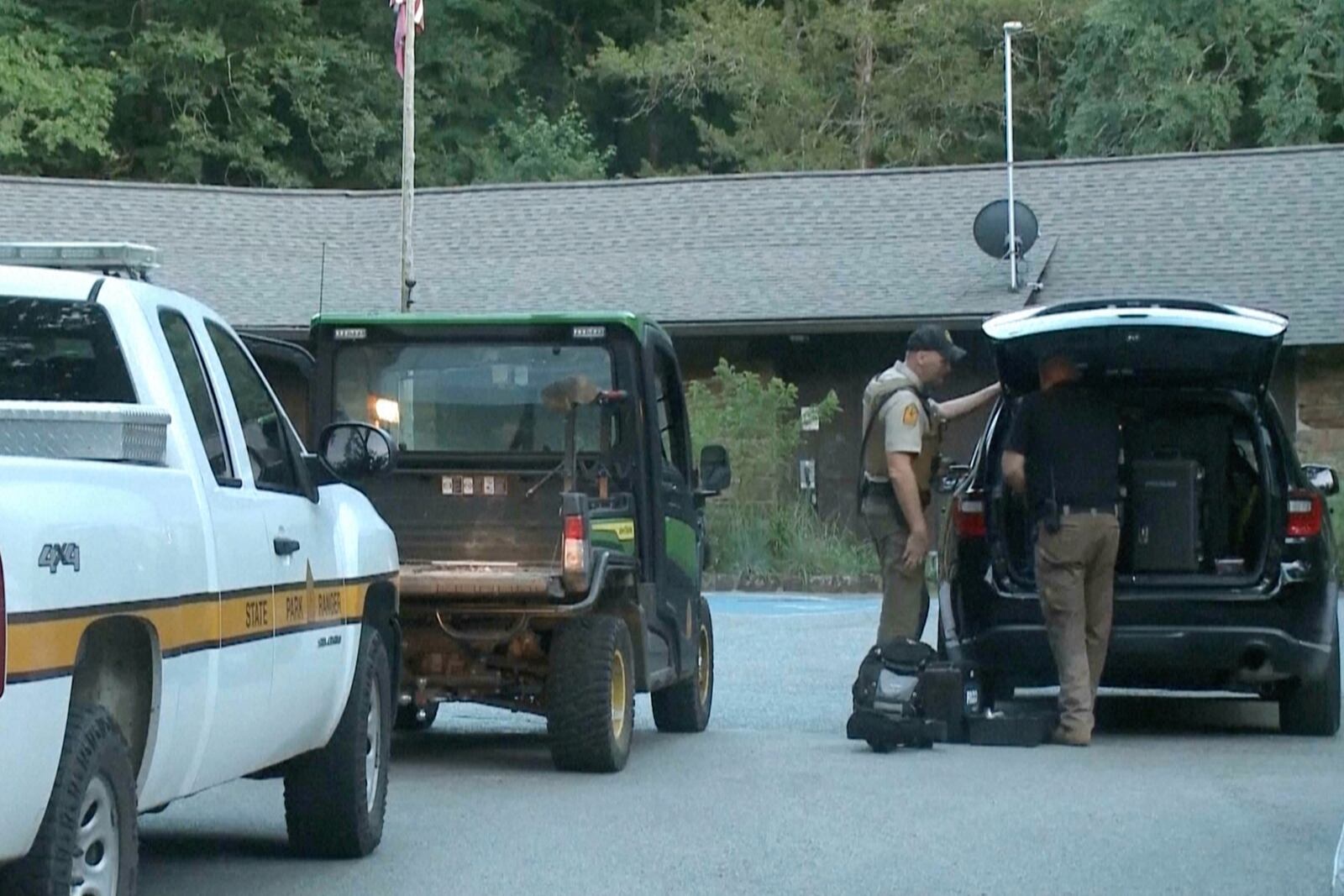 In this image made from video taken on Saturday, July 26, 2025, provided by KHBS/KHOG, law enforcement officers investigate the deaths of a couple who were attacked while on a wooded walking trail with their two young daughters at Devil's Den State Park in West Fort, Ark. (KHBS/KHOG via AP)