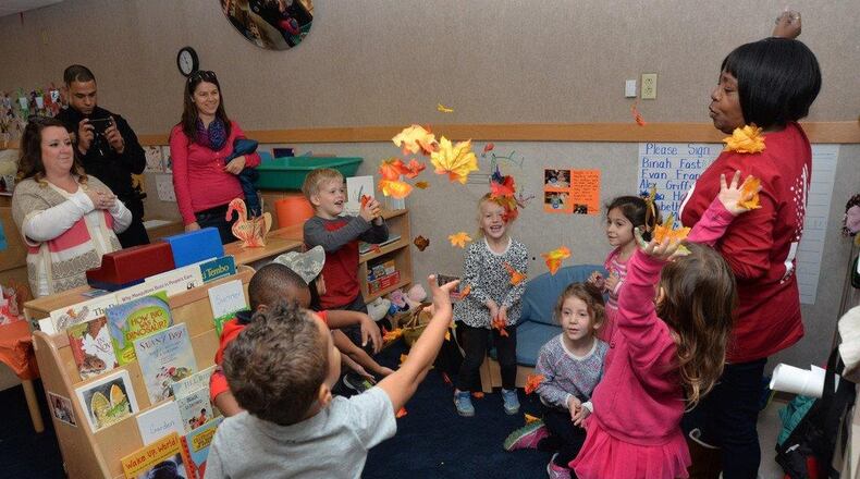 Angela Wilson, lead preschool teacher at New Horizons Child Development Center, and her class sing a fall jingle and toss leaves in celebration of the Harvest Luncheon, Nov. 20, 2015, Wright-Patterson Air Force Base. The CDC provided the event as an opportunity for parents to come and spend time with their children and enjoy a family-style lunch in the classrooms. (U.S. Air Force photo/Michelle Gigante)
