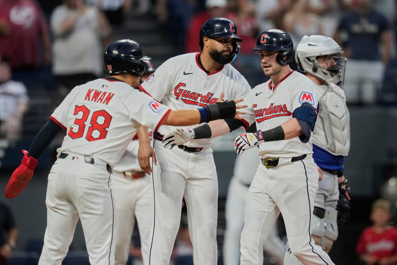Cleveland Guardians' Lane Thomas, right, is greeted by Steven Kwan (38) and Johnathan Rodriguez, center, in front of Toronto Blue Jays catcher Alejandro Kirk after hitting a home run in the seventh inning of a baseball game in Cleveland, Tuesday, June 24, 2025. (AP Photo/Sue Ogrocki)