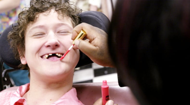 Client Stormie S. is all smiles as Program Specialist Assistant Chelsea Millard adds lip gloss to her look before the Montgomery County Board of Mental Retardation and Developmental Disabilities (MRDD) Calumet Adult Services Center's second annual spring fashion show in 2020.