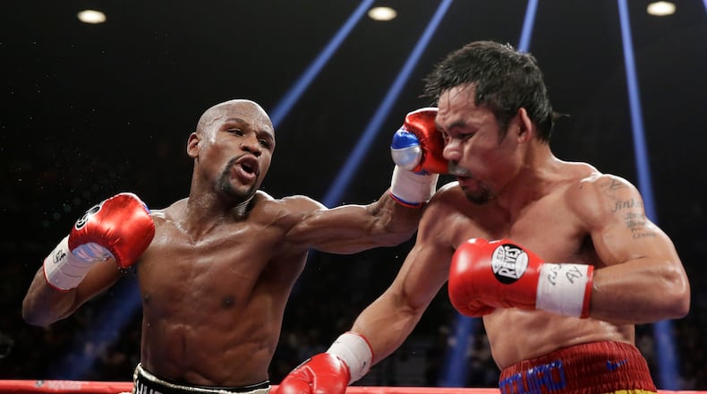 FILE - Floyd Mayweather Jr., left, hits Manny Pacquiao, from the Philippines, during their welterweight title fight on May 2, 2015, in Las Vegas. (AP Photo/Isaac Brekken, File)