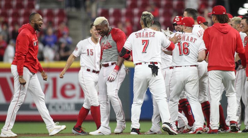 The Reds celebrate after a game-winning hit by Yasiel Puig against the Cubs in the 10th inning on Wednesday, May 15, 2019, at Great American Ball Park in Cincinnati. David Jablonski/Staff