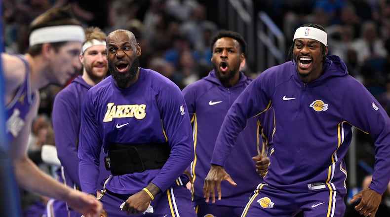 Los Angeles Lakers forward LeBron James, second from front right, and forward Jarred Vanderbilt, right, react after a dunk by guard Austin Reaves, left, during the first half of an NBA basketball game against the Orlando Magic, Saturday, March 21, 2026, in Orlando, Fla. (AP Photo/Phelan M. Ebenhack)