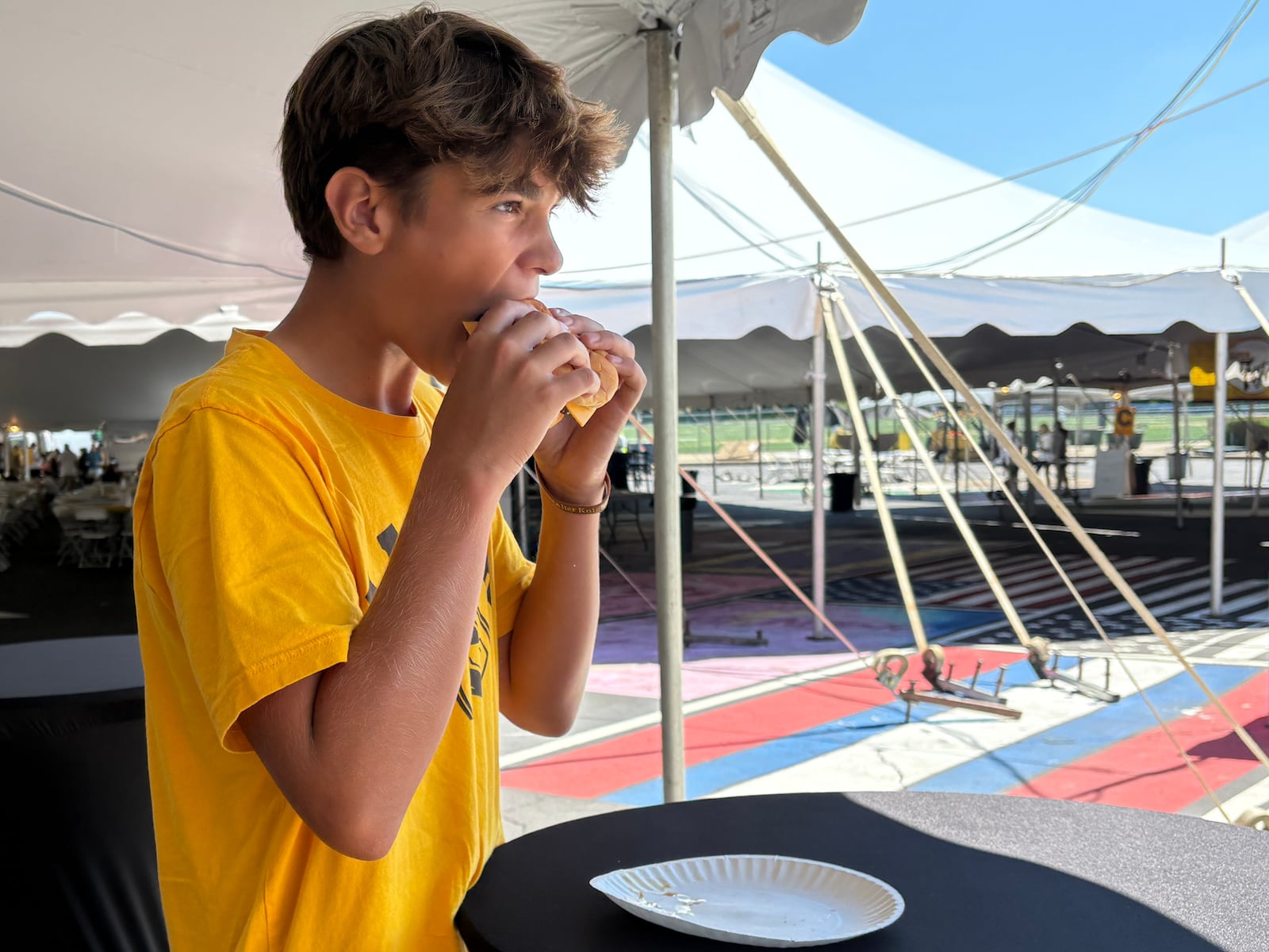 Alter High School freshman Dylan Craft takes a bite out of his cheeseburger Saturday, Aug. 30, 2025, at AlterFest in Kettering. Craft said he's been coming to AlterFest ever since he can remember. JEN BALDUF/STAFF