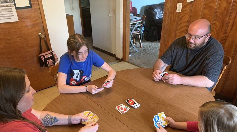 The Spence family, who lives near Trotwood, plays a game of card on a recent Monday afternoon. Playing games together is one of the ways the family has bonded since Ohio Gov. Mike DeWine issued a “stay-at-home” order in March as a way of slowing the COVID-19. The family’s 6-year-old daughter Sydney has struggled with homeschooling and social isolation in recent weeks. From left: Margie Spence, Natalie Reed, Ryan Spence and Sydney Spence./Contributed