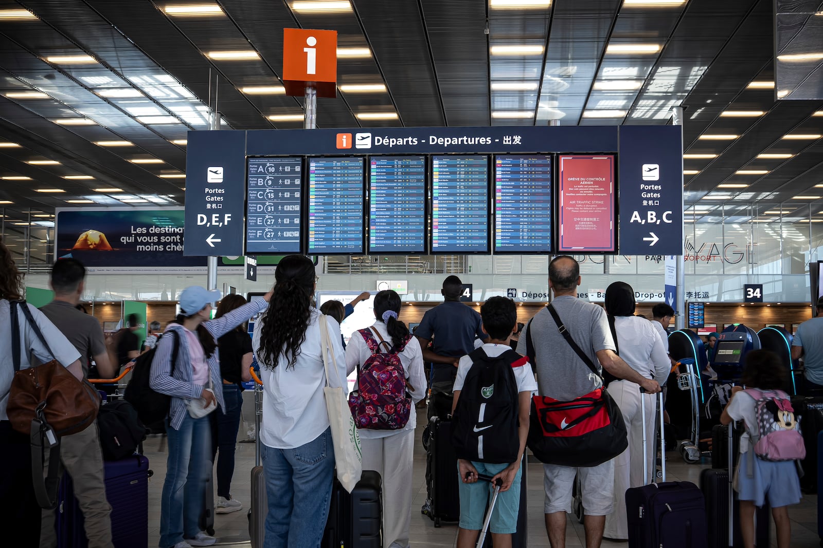 Passengers look a departures information board at Orly airport, near Paris, as French air traffic controllers launched a two-day strike to demand better working conditions, Friday, July 4, 2025. (AP Photo/Aurelien Morissard)