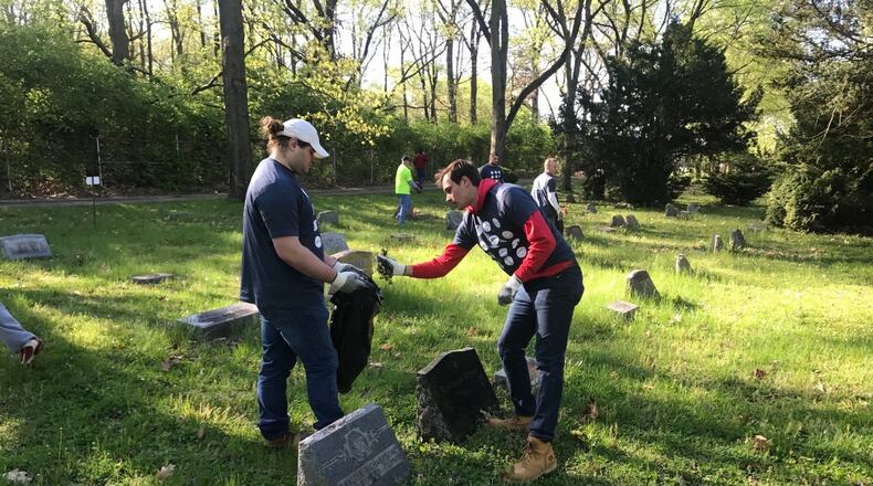 Dayton football players junior offensive lineman Ryan Culhane (left) and senior quarterback Will Bobek (right) clean up Ray Brown’s grave Saturday. Tom Archdeacon/CONTRIBUTED
