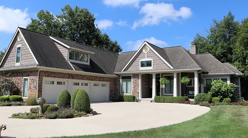 The stone-and-frame house built into a hillside on a 1-acre lakeside lot has about 4,365 sq. ft. of living space. A concrete circular driveway with extra parking pad leads up to the 3-car garage and covered front porch. CONTRIBUTED PHOTO BY KATHY TYLER