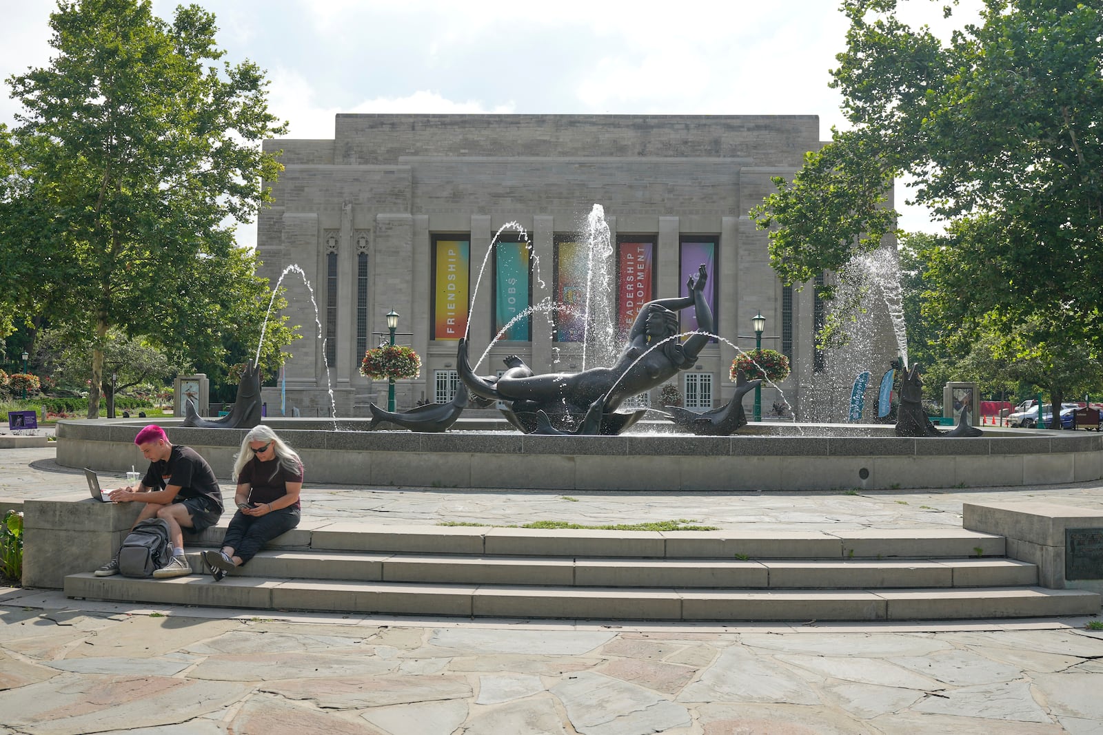 Guests sit by a fountain on the campus of Indiana University, Thursday, July 17, 2025, in Bloomington, Ind. (AP Photo/Darron Cummings)