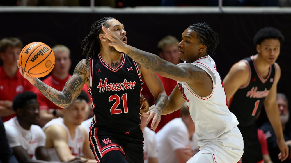 Houston guard Emanuel Sharp, left, looks to pass around the defense of Utah forward Kendyl Sanders, right, during the first half of an NCAA college basketball game, Tuesday, Feb. 10, 2026, in Salt Lake City. (AP Photo/Tyler Tate)