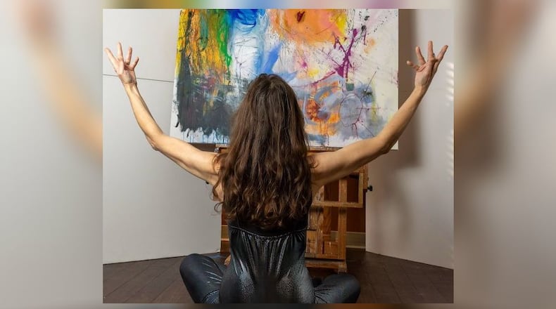 Artist Elyssa Wortzman meditating in front of her painting.