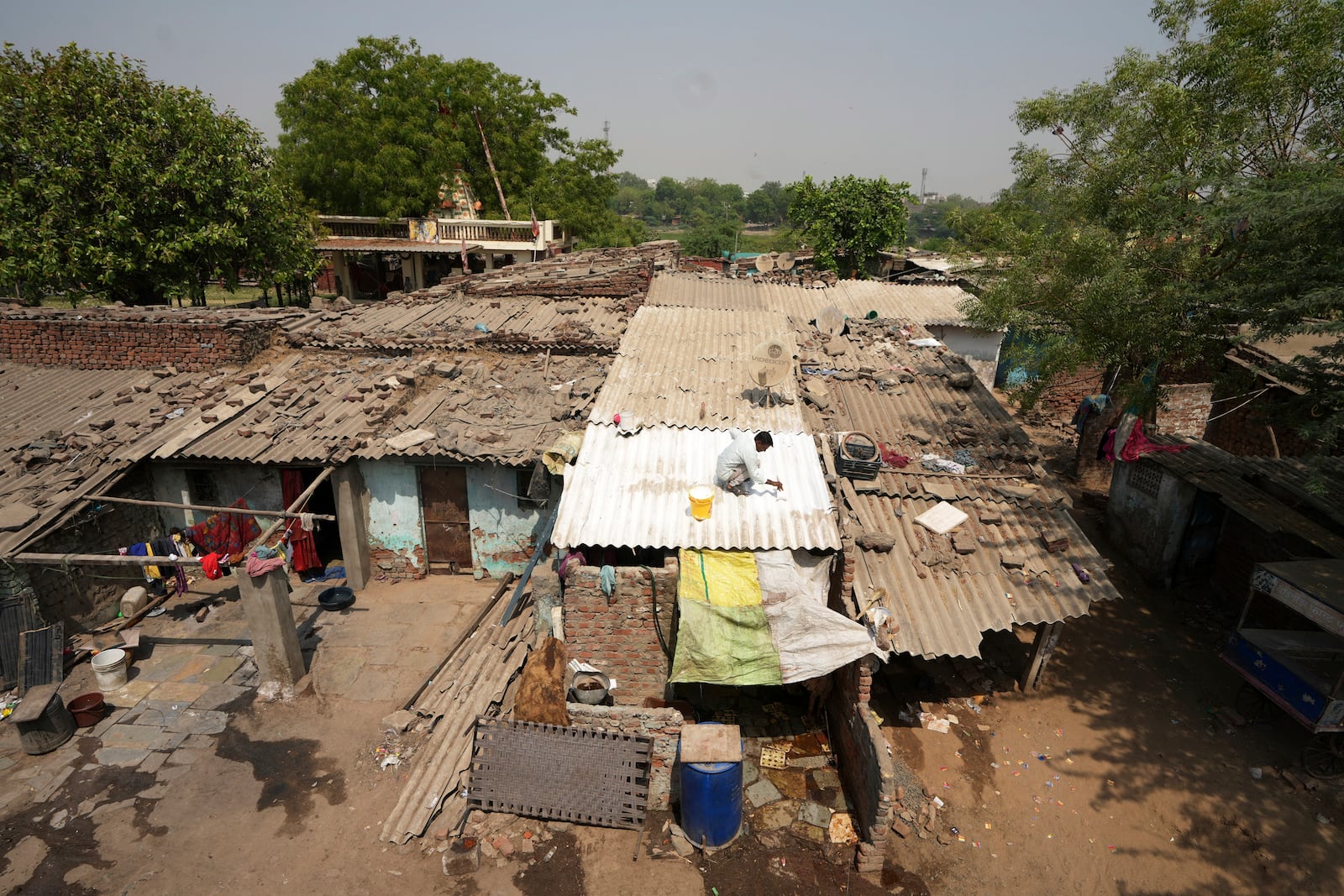 A man applies reflective paint to the roof of a house that helps keep the indoors cooler in Ahmedabad, India, Wednesday, April 2, 2025. (AP Photo/Ajit Solanki)