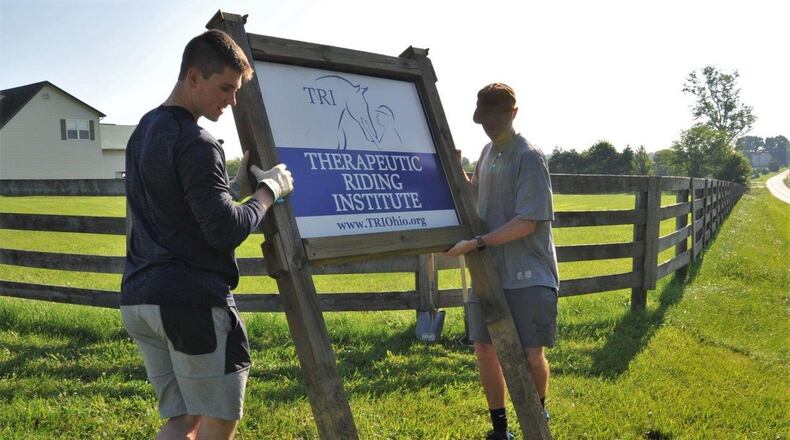 Air Force Academy Cadets Zack LaRocque, left, and Evan Place position a new sign for the Therapeutic Riding Institute to mark the locations needed to dig holes. After quality time with shovels, the duo were able to permanently place the institute s sign at the property s entrance. LaRocque, Place and 18 fellow cadets travelled to Spring Valley July 6 to volunteer with the institute, readying its new location to begin operations. (U.S. Air Force photo/John Van Winkle)